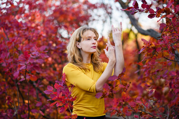 Blonde woman meditate in red autumn forest