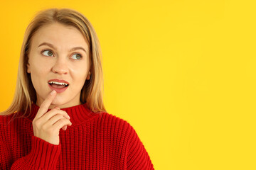 Attractive girl in red sweater on yellow background, space for text