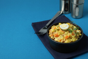 Concept of tasty food with Olivier salad on blue background