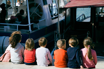 groupe d'enfants regardant les bateaux sur un quai - obrazy, fototapety, plakaty