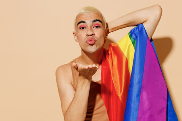 Young boyfriend twink blond latin gay man with make up in beige tank shirt with rainbow flag on...
