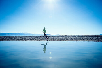 Woman trail runner running in winter lakeside