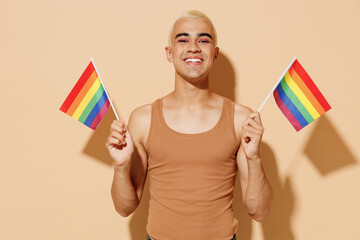 Young smiling happy cheerful blond latin gay man 20s with make up in beige tank shirt holding...