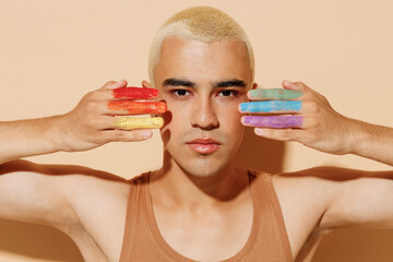 Young smiling happy fun blond latin gay man wear beige tank shirt posing with make up fingers...