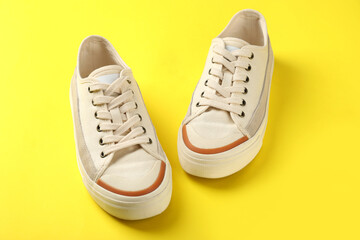 Pair of beige sneakers on yellow background