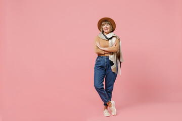 Full size body length traveler tourist vivid mature elderly senior lady woman 55 years old wear brown shirt hat scarf hold hands crossed isolated on plain pastel light pink background studio portrait