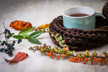 autumn leaves, berries, tea in a mug on a wooden background