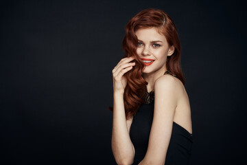 attractive red-haired woman in a black dress hairstyle dark background