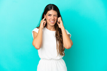 Young caucasian woman isolated on blue background frustrated and covering ears