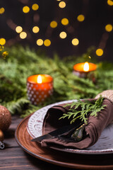 Christmas table setting with decorations, fir branches and candles.
