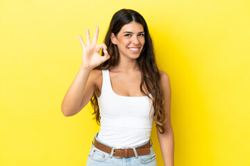 Young caucasian woman isolated on yellow background showing ok sign with fingers