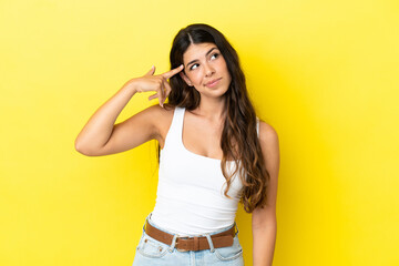 Young caucasian woman isolated on yellow background making the gesture of madness putting finger on the head