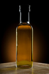 Full olive oil bottle with on timber bench with yellow spot background