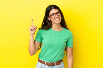 Young caucasian woman isolated on yellow background showing and lifting a finger in sign of the best