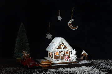 New Years composition: gingerbread house, toy car, artificial Christmas tree.