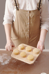 Woman showing wooden board with decorated raw mooncakes she make for mid autumn festival