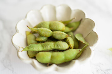 白いお皿に盛り付けた新鮮な枝豆（丹波篠山の黒枝豆）