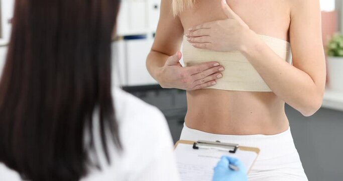 Woman with elastic bandage on her chest showing breast doctor to mammologist 4k movie