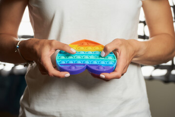 Close-up photo of a toy "Pop it" in the shape of a heart in the hands of a girl