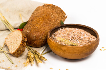 Spelt bran in the bowl, whole grain bread and spelt ears on sackcloth. Organic spelt flakes. Cereal products on white background.