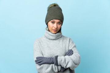 Young Uruguayan girl with winter hat isolated on blue background keeping arms crossed