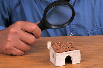 Concept d'état des lieux d'une maison avec un homme examinant une petite maison avec une loupe