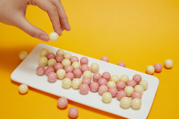 Hand-picking up colorful candy coated chocolates buttons from a bowl. Copy space.