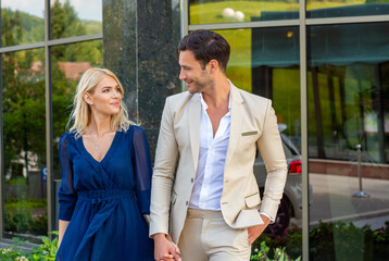 Attractive couple holding hands leaving hotel