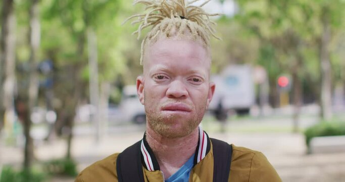 Portrait of albino african american man with dreadlocks in park looking at camera