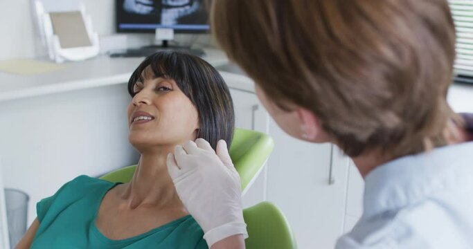 Caucasian female dental nurse talking with female patient at modern dental clinic