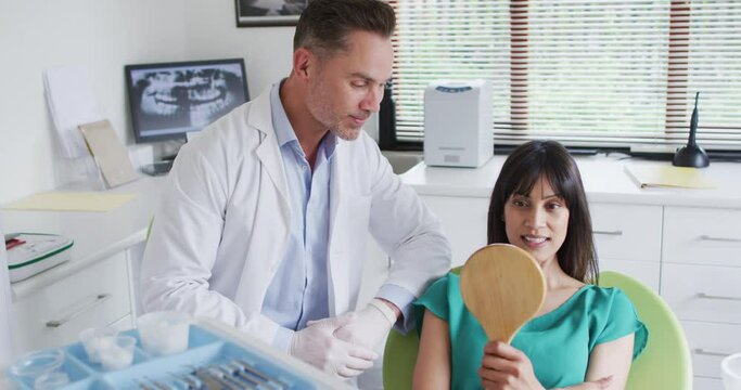 Smiling caucasian male dentist talking with female patient at modern dental clinic