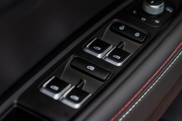 Close up view of button controlling window in modern car interior. Vehicle interior detail. Door handle with windows controls