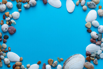 Flat lay composition sea pebbles and seashells on a blue background. space for text