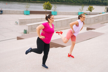 Personal fitness female trainer helping fat woman lose weight outside taking step exercising on city stairs in summer morning. Instructor giving training to overweight young woman outside.