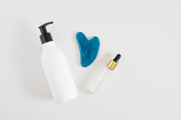 moisturizer in a dispenser bottle, serum in a dropper bottle and massager guasha scraper. Self-care set