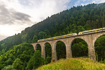 Historic railway bridge with a yellow train at the Ravenna Gorge Black Forest