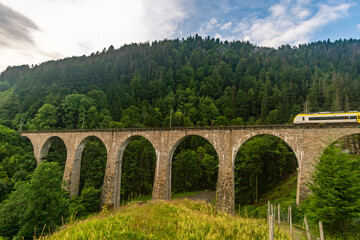 Fototapeta na wymiar Historic railway bridge with a yellow train at the Ravenna Gorge Black Forest