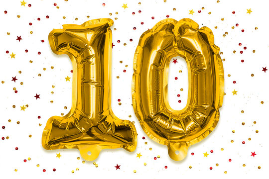 The number of the balloon made of golden foil, the number ten on a white background with multicolored sequins. Birthday greeting card with inscription 10. Anniversary concept. Celebration event. - Powered by Adobe