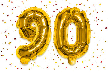 The number of the balloon made of golden foil, the number ninety on a white background with...