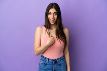 Naklejka premium Young caucasian woman isolated on purple background with surprise facial expression
