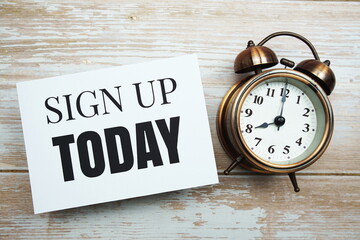 Sign up Today text and alarm clock on wooden background