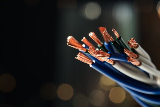 Stranded copper wires with insulation against blurred background, closeup. Space for text