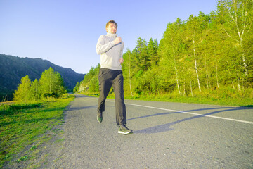 Running man jogging in city park at beautiful summer day. Sport fitness model caucasian ethnicity training outdoor.