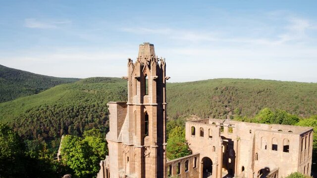 Cinematic Drone Shot of Tower of Limbach Monastery Ruin with Green Hills in Background and Blue Sky