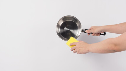 Pot cleaning. Man hand on white background cleaning the non stick pot with handy dish washing sponge which yellow color on the soft side and green on hard side for hygiene after cook. Electric pot. 