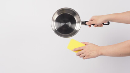 Pot cleaning. Man hand on white background cleaning the non stick pot with handy dish washing sponge which yellow color on the soft side and green on hard side for hygiene after cook. Electric pot. 