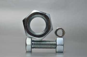 composition of new bolts and nuts of different sizes on a gray background.