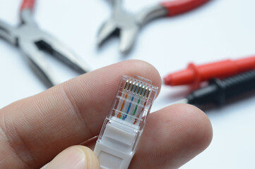 internet cable with a connector rj 45 in the hand of the master. against the background of tools.