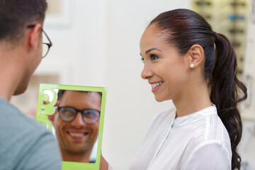 adult consultant and male customer choosing glasses in optics store
