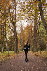 girl in dark clothes among tall autumn trees